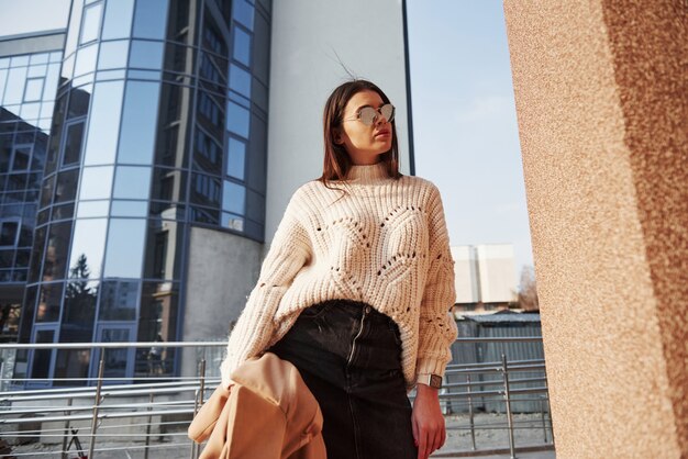 Gafas caras. Hermosa joven en ropa de abrigo tiene caminar en la ciudad en su tiempo de los fines de semana