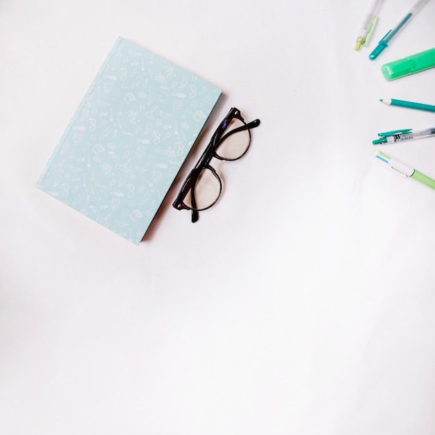 Gafas cerca de notebook y bolígrafos