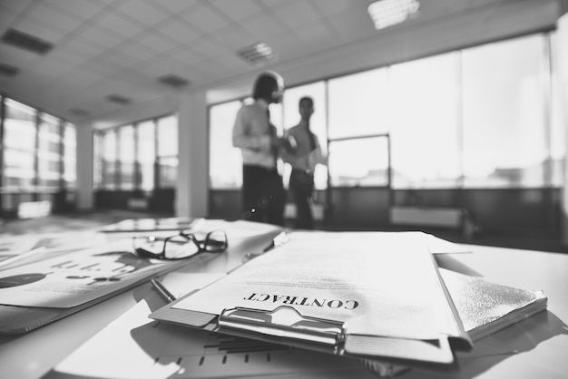 Foto gratuita gafas en un escritorio de oficina repleto de papeles en blanco y negro