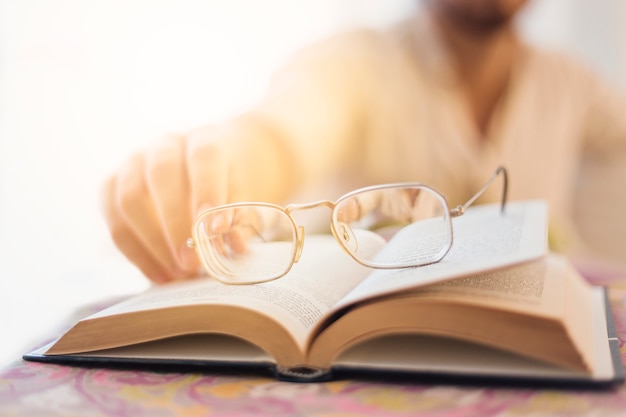 Gafas en libro con hombre borroso al fondo