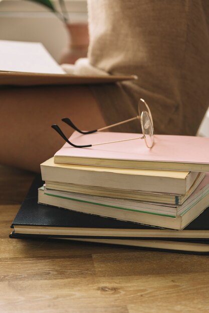 Gafas y libros cerca de mujer de cultivo