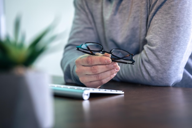 Foto gratuita gafas en manos masculinas en el lugar de trabajo frente a la computadora