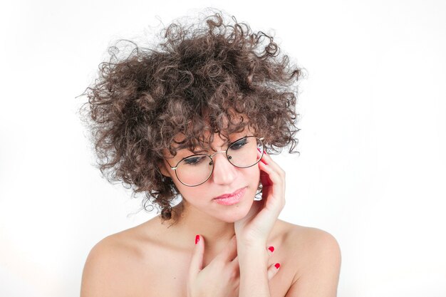 Gafas que llevan de la mujer hermosa joven contra el fondo blanco