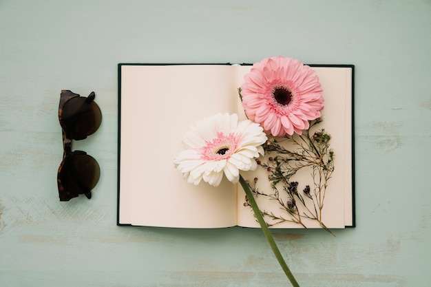 Gafas de sol cerca de cuaderno y flores