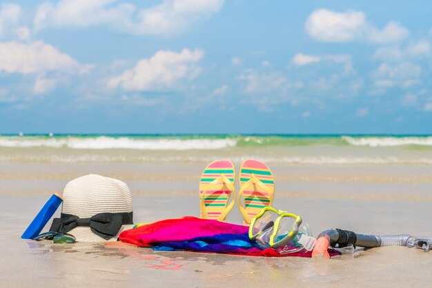 Gafas de sol, crema solar y sombrero en la playa de arena blanca