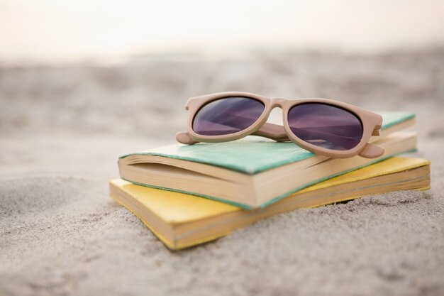 Gafas de sol y libros sobre la arena