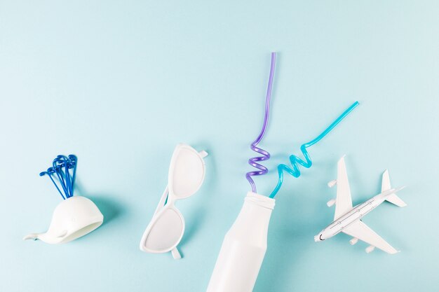Gafas de sol ornamentales cerca de avión de juguete con ballena y botella con pajitas