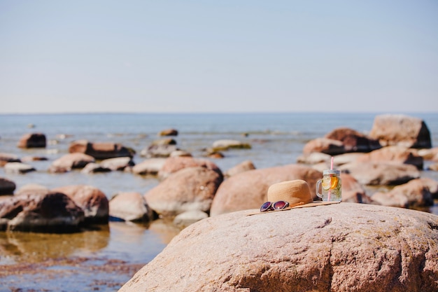 Gafas de sol, sombrero y bebida refrescante en la playa