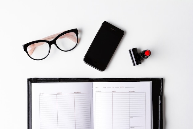 Foto gratuita gafas de teléfono de lápiz labial rojo y portátil sobre superficie blanca arriba.