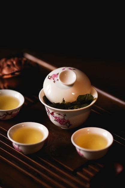 Gaiwan de porcelana, tres tazas de té chino y rana dorada en el escritorio del té.
