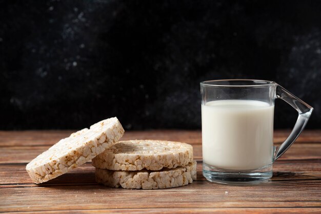 Galleta de arroz y vaso de leche en la mesa de madera.