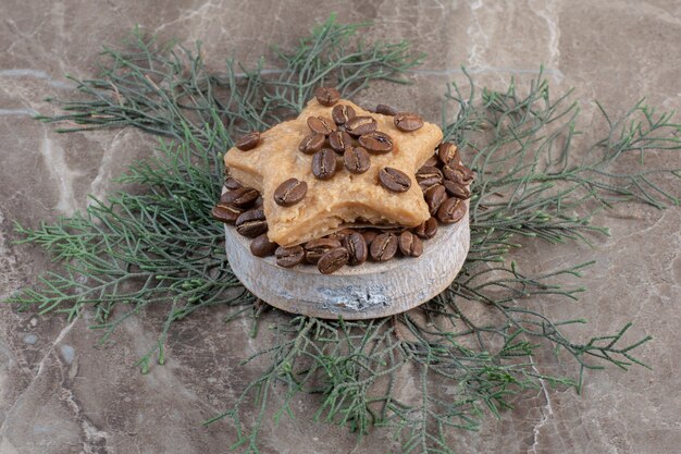 Galleta en forma de estrella sobre un montón de granos de café sobre un pequeño pedestal de mármol.