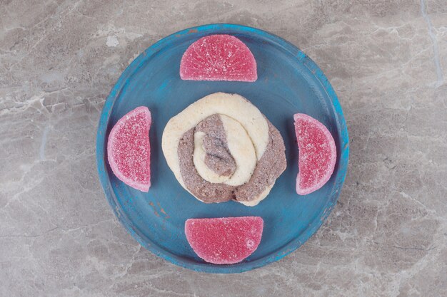 Una galleta y unas mermeladas en una bandeja azul sobre mármol '