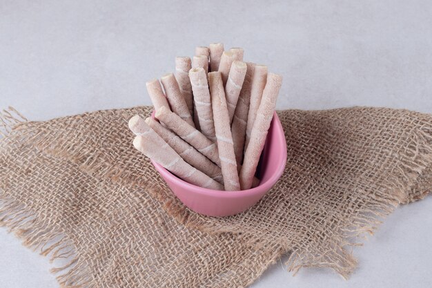 Galleta de oblea pirouline de chocolate y avellana en un tazón, sobre una toalla, sobre el mármol.