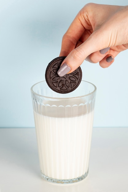 Foto gratuita galleta sostenida por encima del vaso de leche a largo plazo tiro