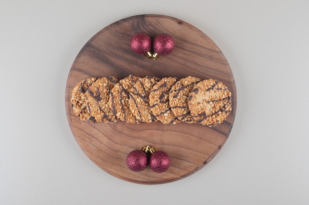 Galletas y adornos navideños sobre una tabla de madera sobre fondo blanco.