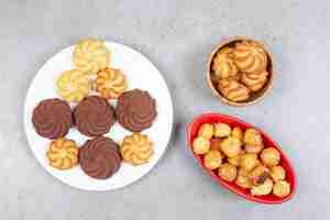 Foto gratuita galletas agrupadas en varios vajillas sobre superficie de mármol.