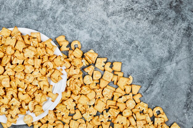 Galletas del alfabeto dispersas en un plato blanco y.