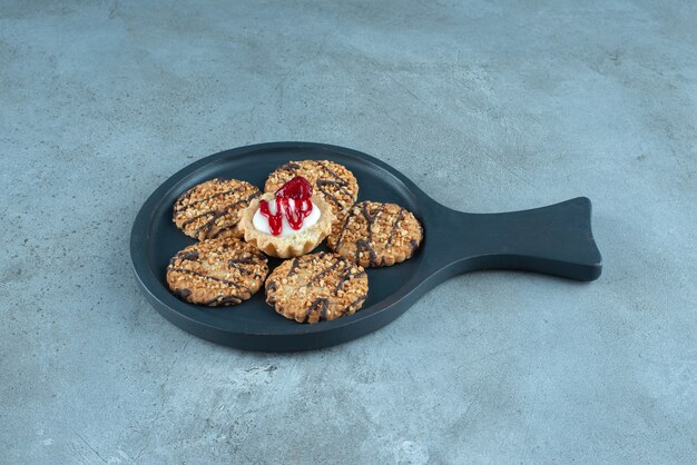 Galletas alrededor de un cupcake en una bandeja pequeña sobre superficie de mármol