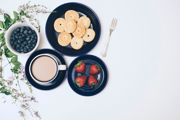 Galletas; arándanos; Café y fresas sobre fondo blanco.