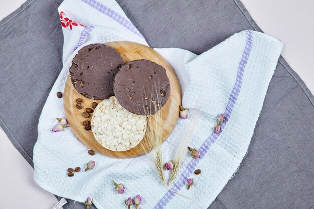 Galletas de arroz y chocolate en una placa de madera con un mantel.