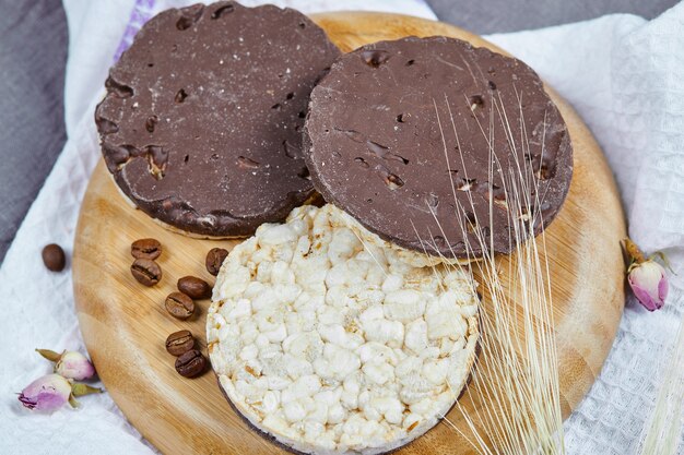 Galletas de arroz y chocolate en una placa de madera con un mantel.