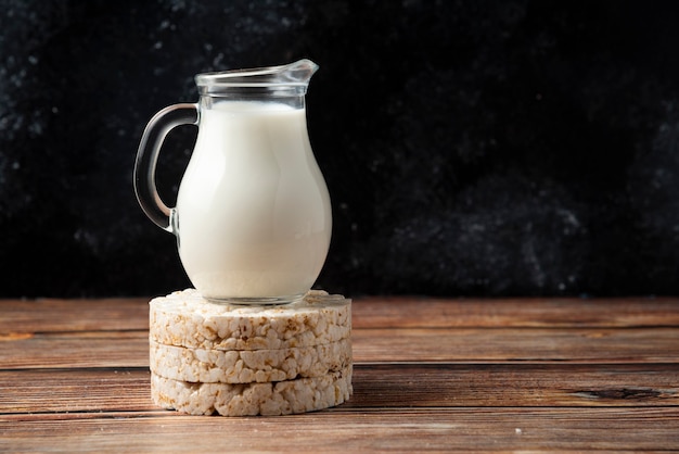 Galletas de arroz y jarra de leche en la mesa de madera.