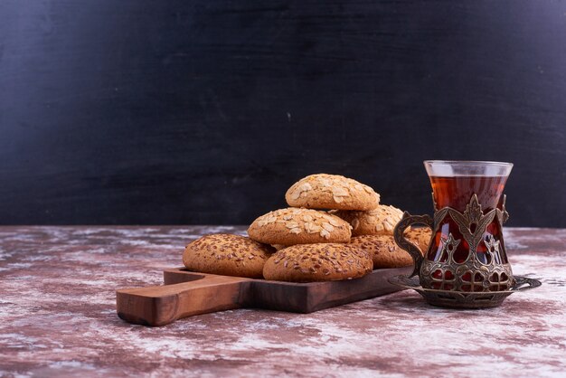 Galletas de avena en una bandeja de madera con un vaso de té.