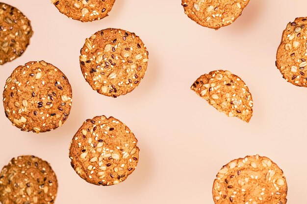 Galletas de avena caseras con semillas de lino, girasol y sésamo sobre papel pintado color nude. Concepto de comida sana fitness. Leche y galletas caseras para el desayuno en capas sobre fondo de color nude