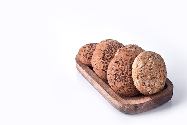 Galletas con avena y comino en bandeja de madera sobre blanco.