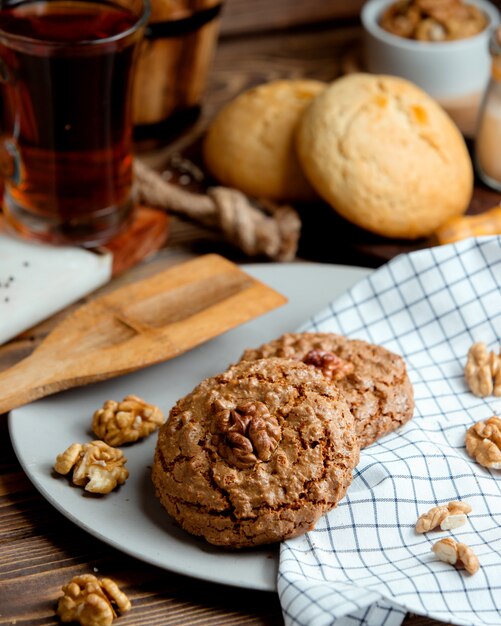 Galletas de avena con nueces y una taza de té aromático.