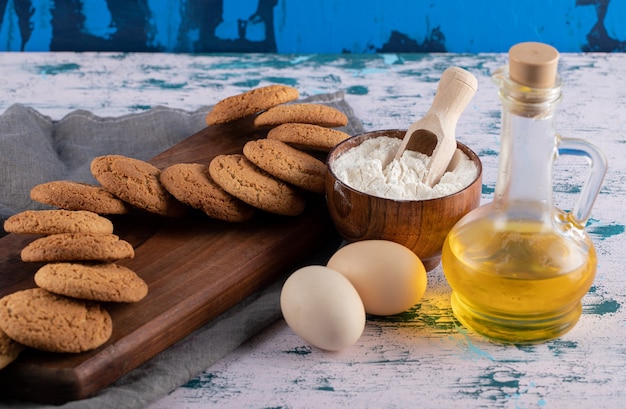 Galletas de avena en un plato de madera con ingredientes alrededor.