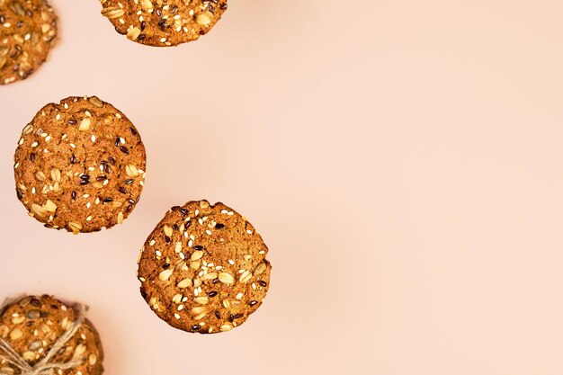 Galletas de avena con semillas de lino, girasol y sésamo sobre papel tapiz de color nude con espacio para copiar texto. Concepto de comida sana fitness. Leche y galletas caseras para el desayuno.