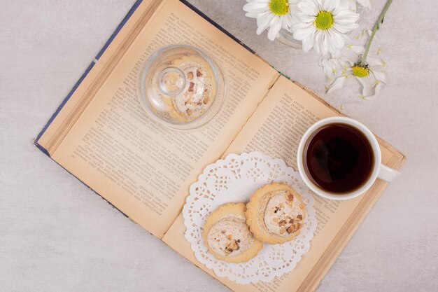 Galletas de avena y taza de té en libro abierto.