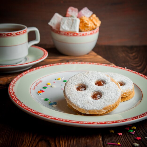 galletas de azúcar en polvo con una taza de té y azúcar en un plato redondo