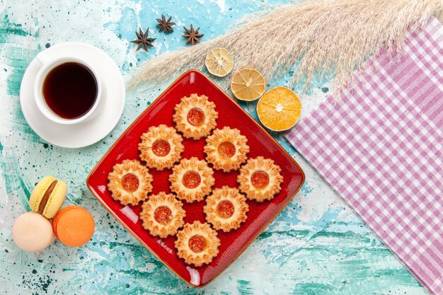 Galletas de azúcar de vista superior con taza de té y macarons en el fondo azul