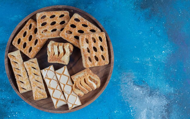 Galletas en la bandeja de madera, sobre fondo azul. Foto de alta calidad