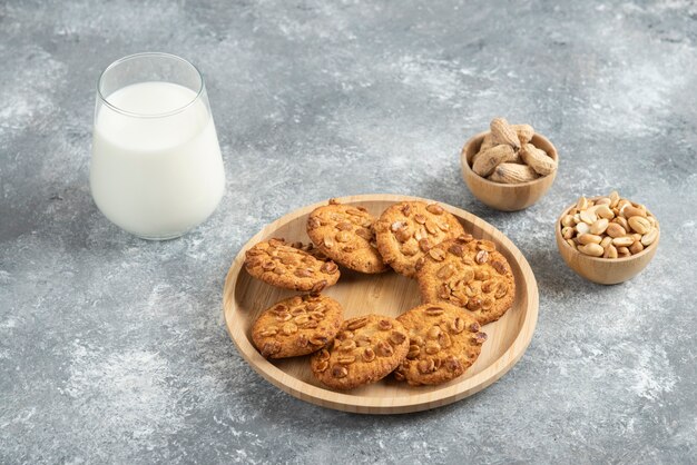 Galletas con cacahuetes orgánicos y vaso de leche en la mesa de mármol.