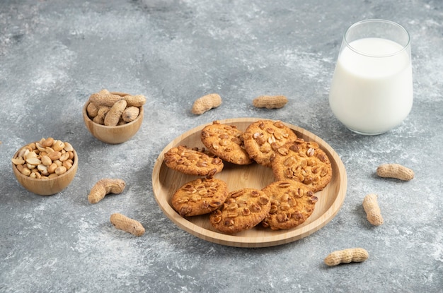 Foto gratuita galletas con cacahuetes orgánicos y vaso de leche en la mesa de mármol.