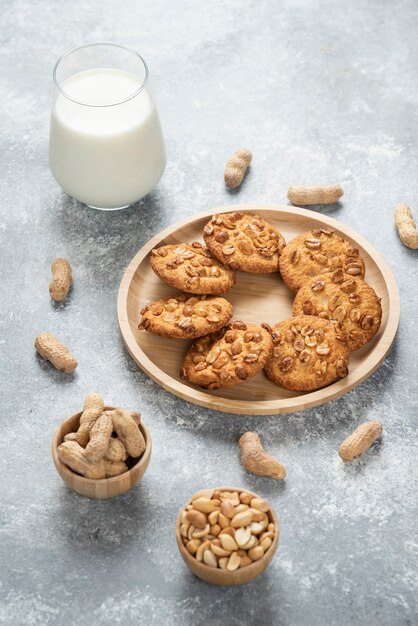 Galletas con cacahuetes orgánicos y vaso de leche en la mesa de mármol.