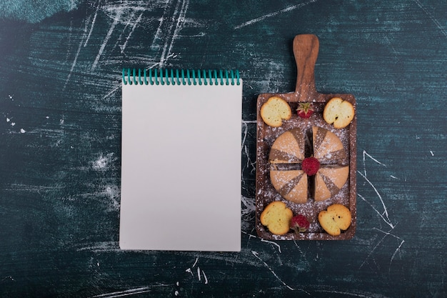 Galletas de cacao y vainilla sobre una tabla de madera con un cuaderno a un lado