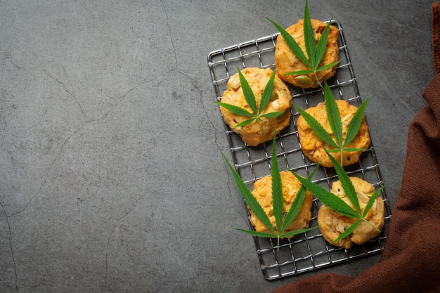 Galletas de cannabis y hojas de cannabis en suelo oscuro