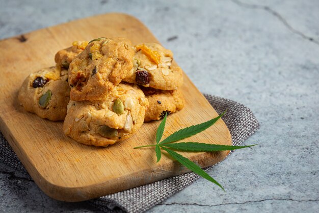 Galletas de cannabis y hojas de cannabis en tabla de cortar de madera