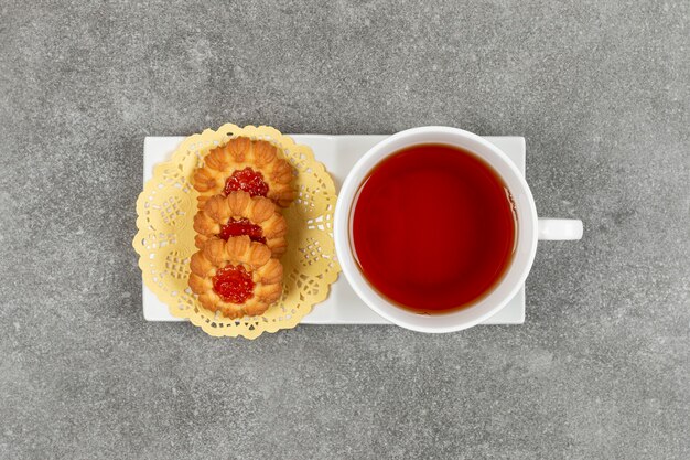 Foto gratuita galletas caseras con gelatina y taza de té en platillo blanco