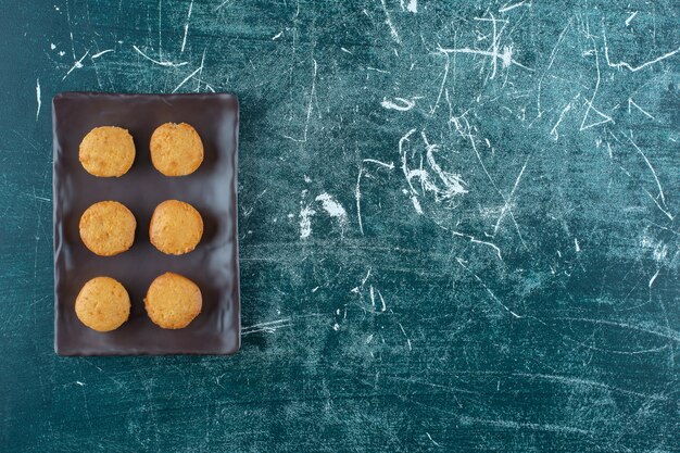 Galletas caseras en una placa negra, sobre fondo azul. Foto de alta calidad