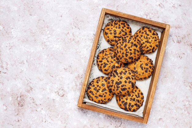 Galletas de chispas de chocolate de estilo americano en bandeja de madera sobre fondo de hormigón ligero.