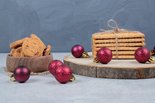 Galletas con chispas de chocolate, pila de galletas y bolas de Navidad en la mesa de mármol. Foto de alta calidad
