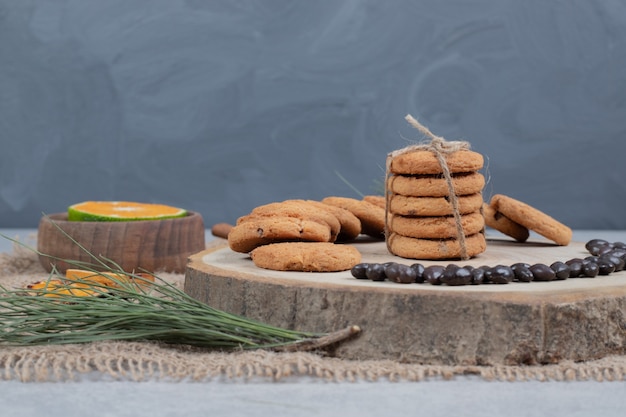 Galletas con chispas de chocolate sobre tabla de madera con granos y rodajas de mandarina. Foto de alta calidad