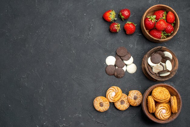 Galletas de choco de vista superior con fresas y galletas en superficie oscura