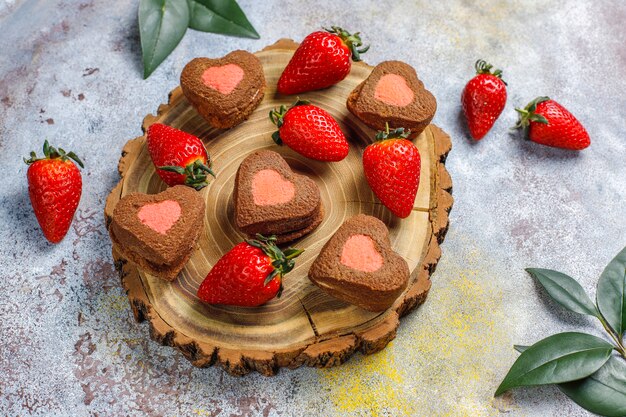 Galletas de chocolate y fresa en forma de corazón con fresas frescas, vista superior